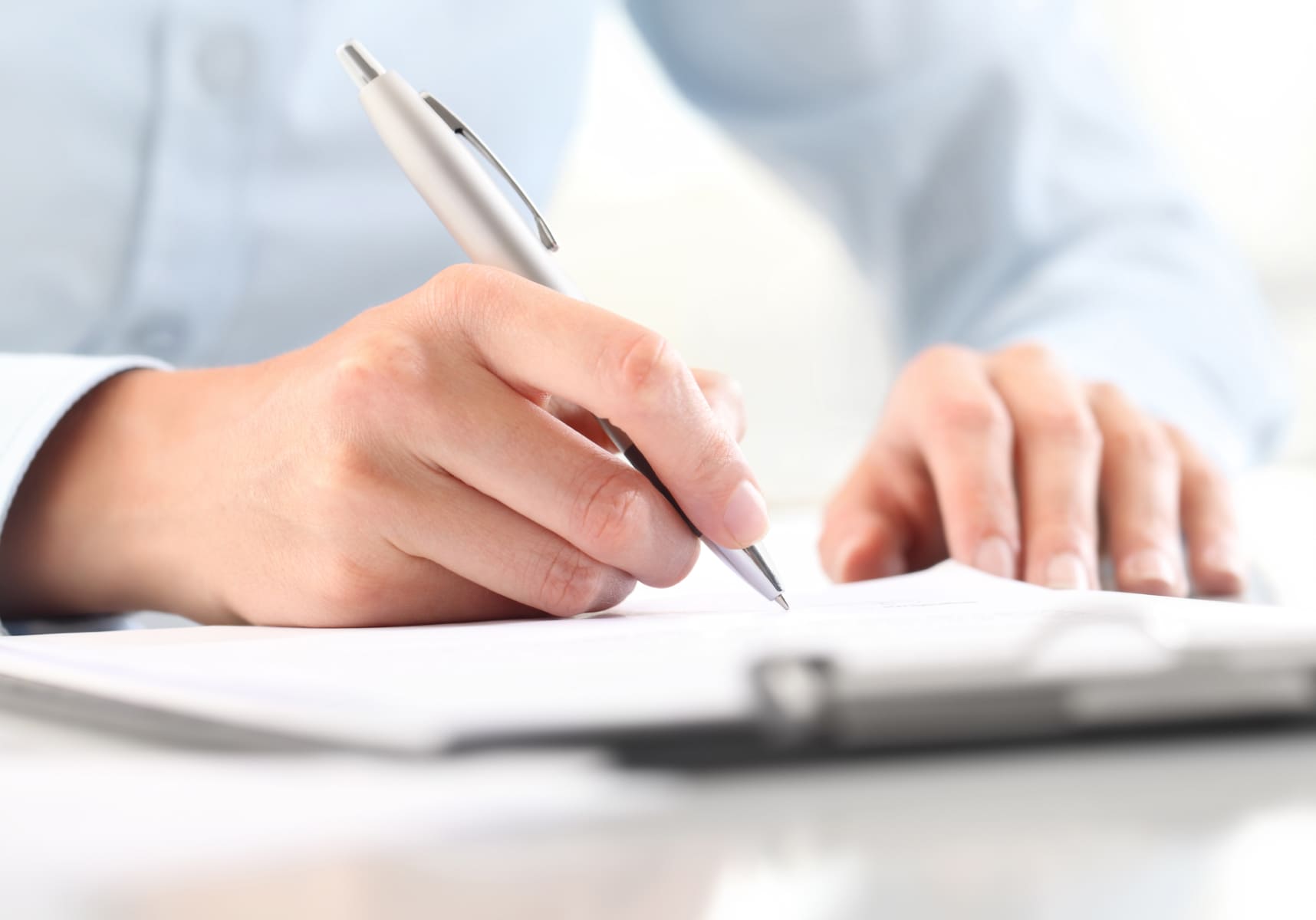 書類にペンで何かを書いている男性の手元